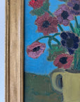 Close up of a framed, vintage artwork of red flowers on a teal blue background.