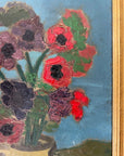 Close up of a framed, vintage artwork of red flowers on a teal blue background.