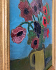 Close up of a framed, vintage artwork of red flowers on a teal blue background.