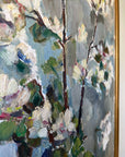 Close up of a framed vintage oil painting of white apple blossom flowers.