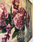 Close up of a vintage oil painting on canvas of a bouquet of dark pink hydrangeas in a glass vase.