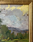 Close up of a framed vintage oil painting of a landscape with trees and a meadow.