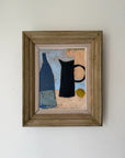 A framed still life painting featuring a blue bottle, a black pitcher, and a small yellow circle on a textured beige and blue background, housed in a rustic brown wooden frame. Available at Hue.
