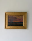 A framed vintage landscape oil painting. The painting depicts a sunset over a field with a dark, moody sky in shades of purple, orange, and brown, enclosed in a gold frame. Available at Hue.