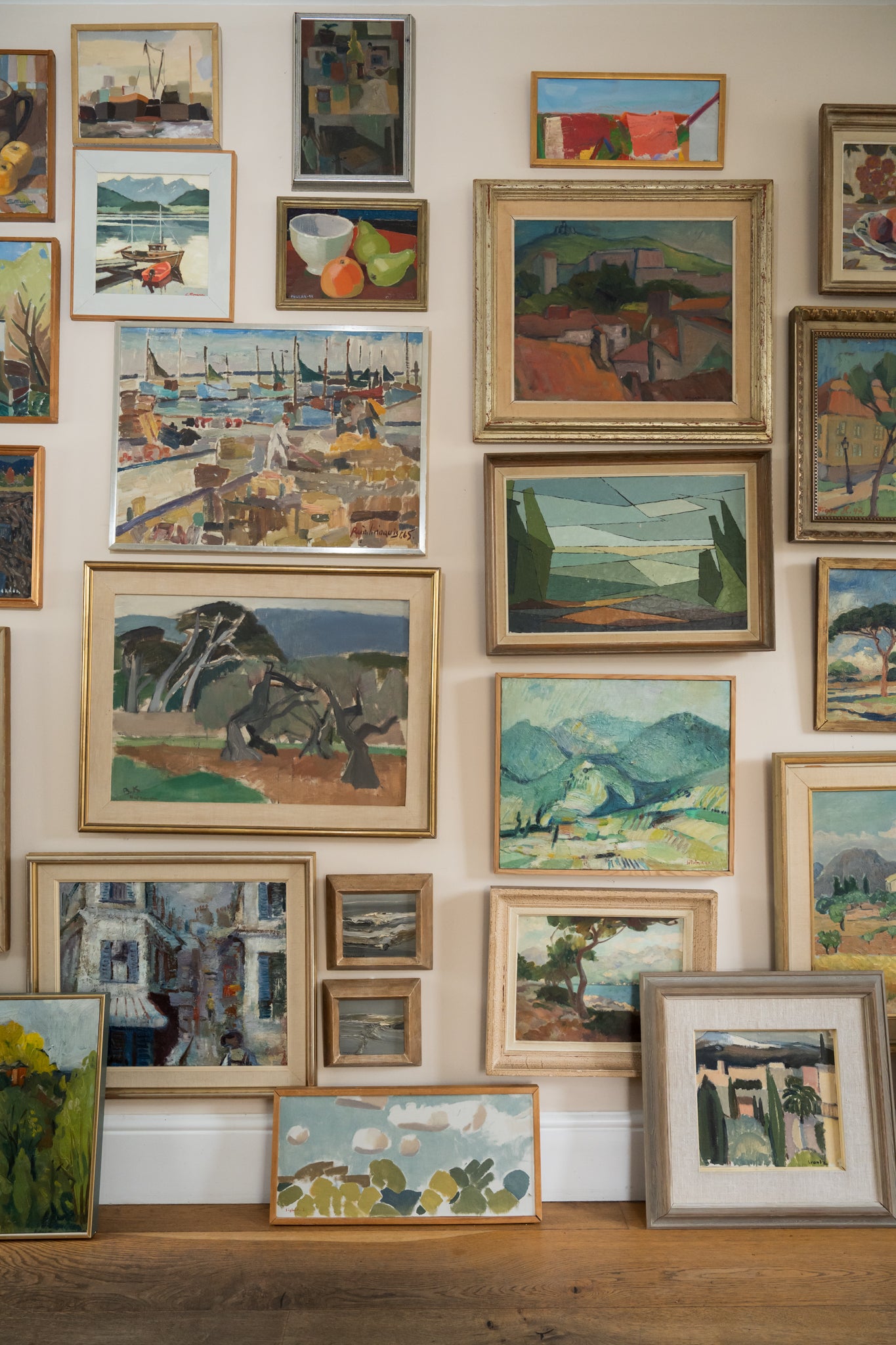 Wall with various framed paintings arranged in a salon hang available from hue.
