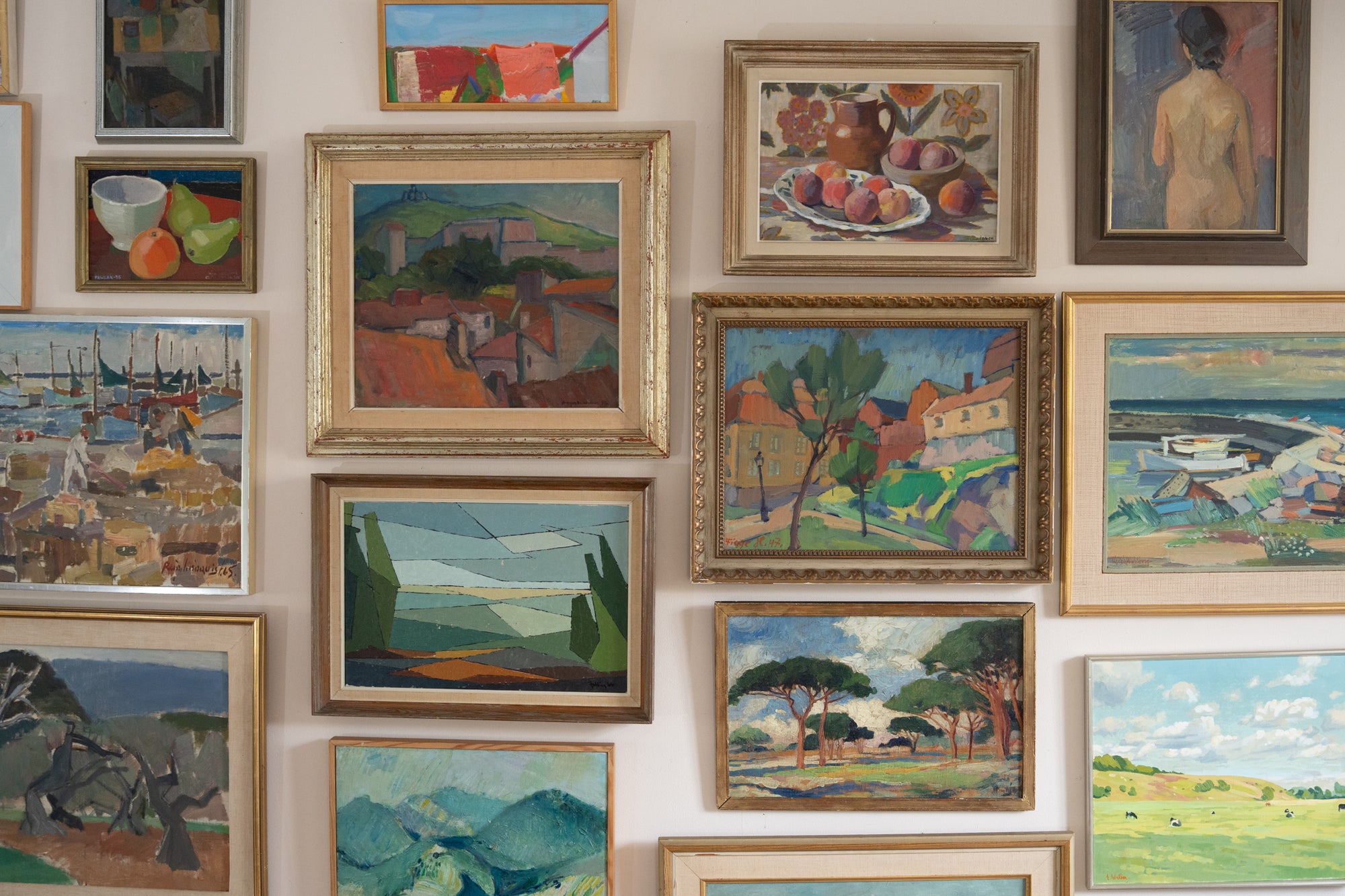 Wall with various framed vintage paintings of landscapes and still lifes