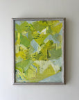Abstract painting with green and blue tones in a silver frame on a white wall available from hue