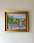 A framed vintage oil painting of a lake shore with pink rocks and landscape beyond. Available at Hue.