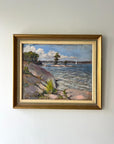 Framed painting of a coastal scene with rocky shore and water on a white wall available from hue
