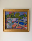 A framed vintage oil painting of a watering can and garden deckchair with pink florals. Available at Hue.