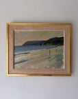 A framed vintage beach landscape painting with a gold frame. The painting depicts a sandy beach, ocean waves, dark cliffs, and a pale sky. Available at Hue.