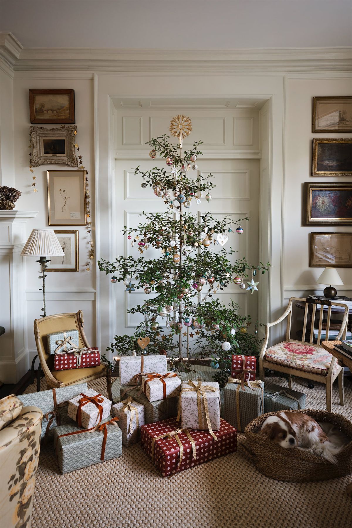 A cosy living room styled for Christmas with framed art, a simple tree and softly wrapped gifts.