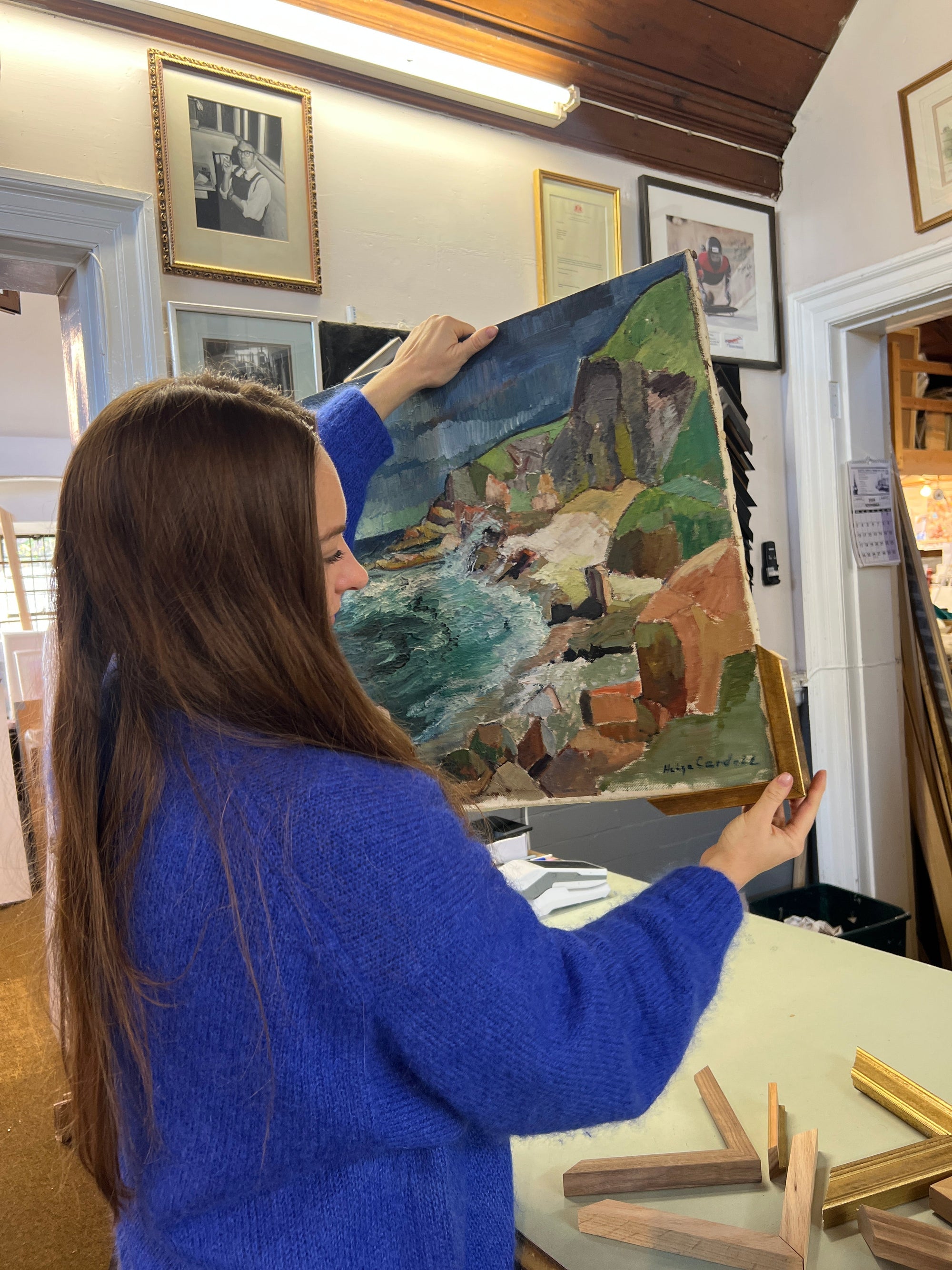 Vintage landscape painting being assessed  for framing at a professional framing studio, showing the importance of framing original art.
