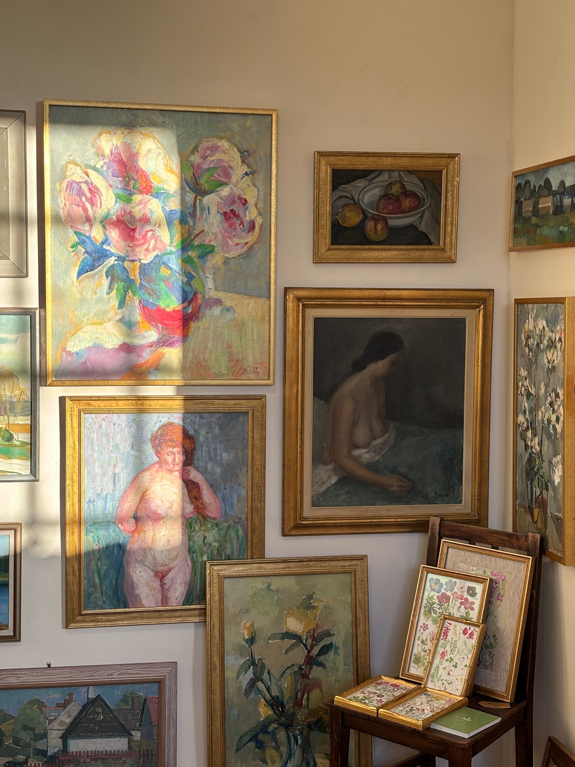 A curated display of framed vintage paintings arranged in a gallery-style hang at the curated store