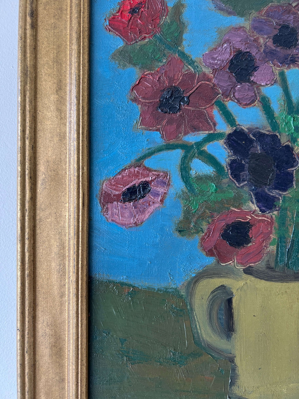 Close up of a framed, vintage artwork of red flowers on a teal blue background.