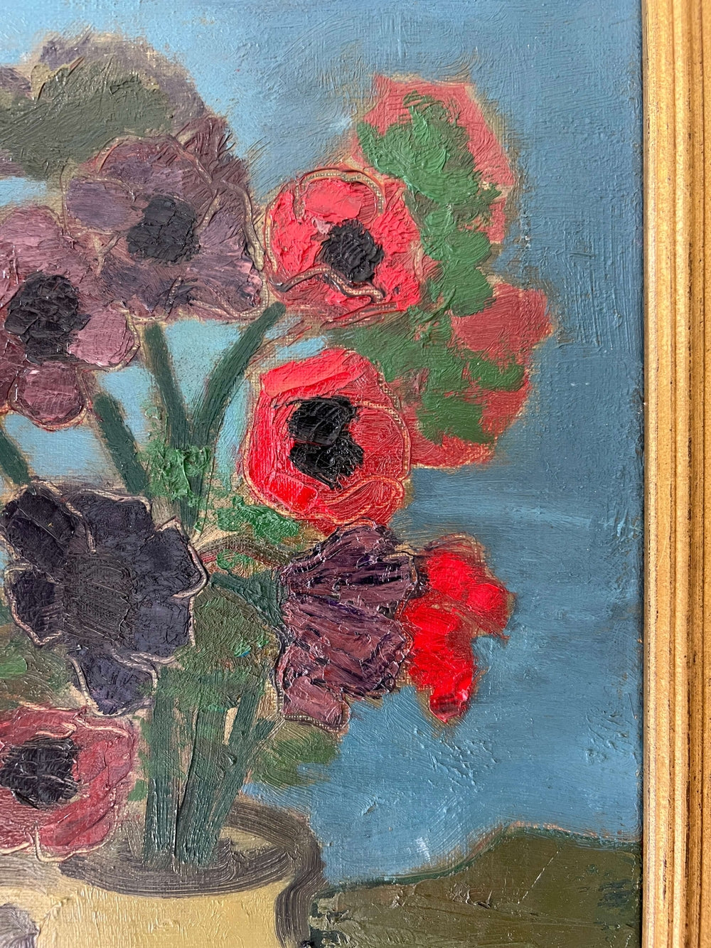 Close up of a framed, vintage artwork of red flowers on a teal blue background.