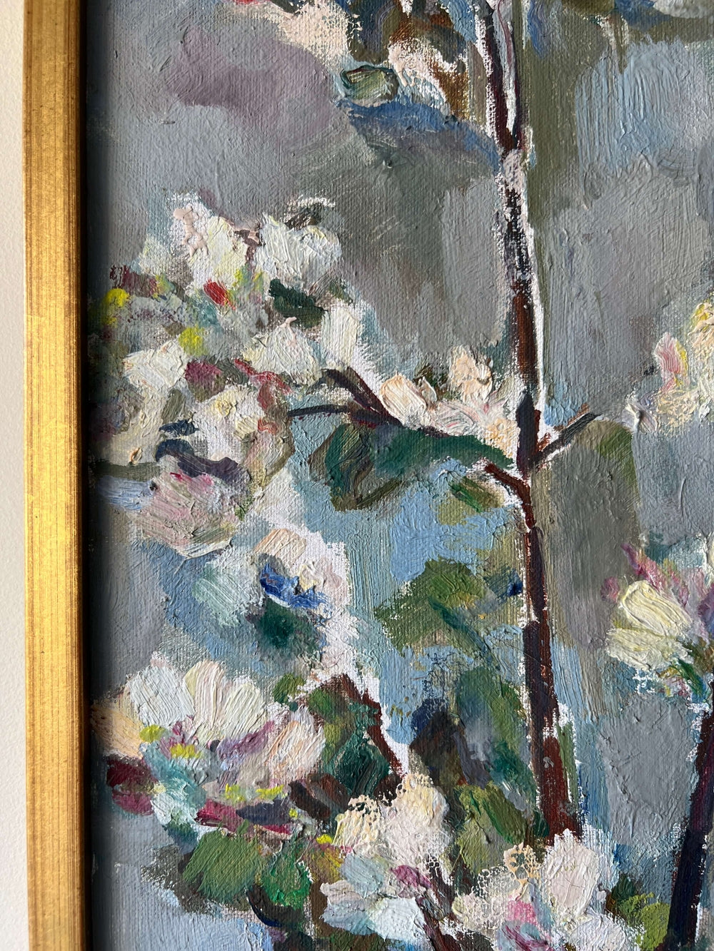 Close up of a framed vintage oil painting of white apple blossom flowers.