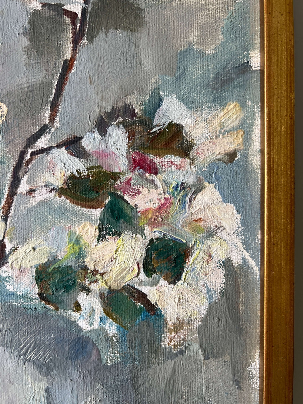 Close up of a framed vintage oil painting of white apple blossom flowers.