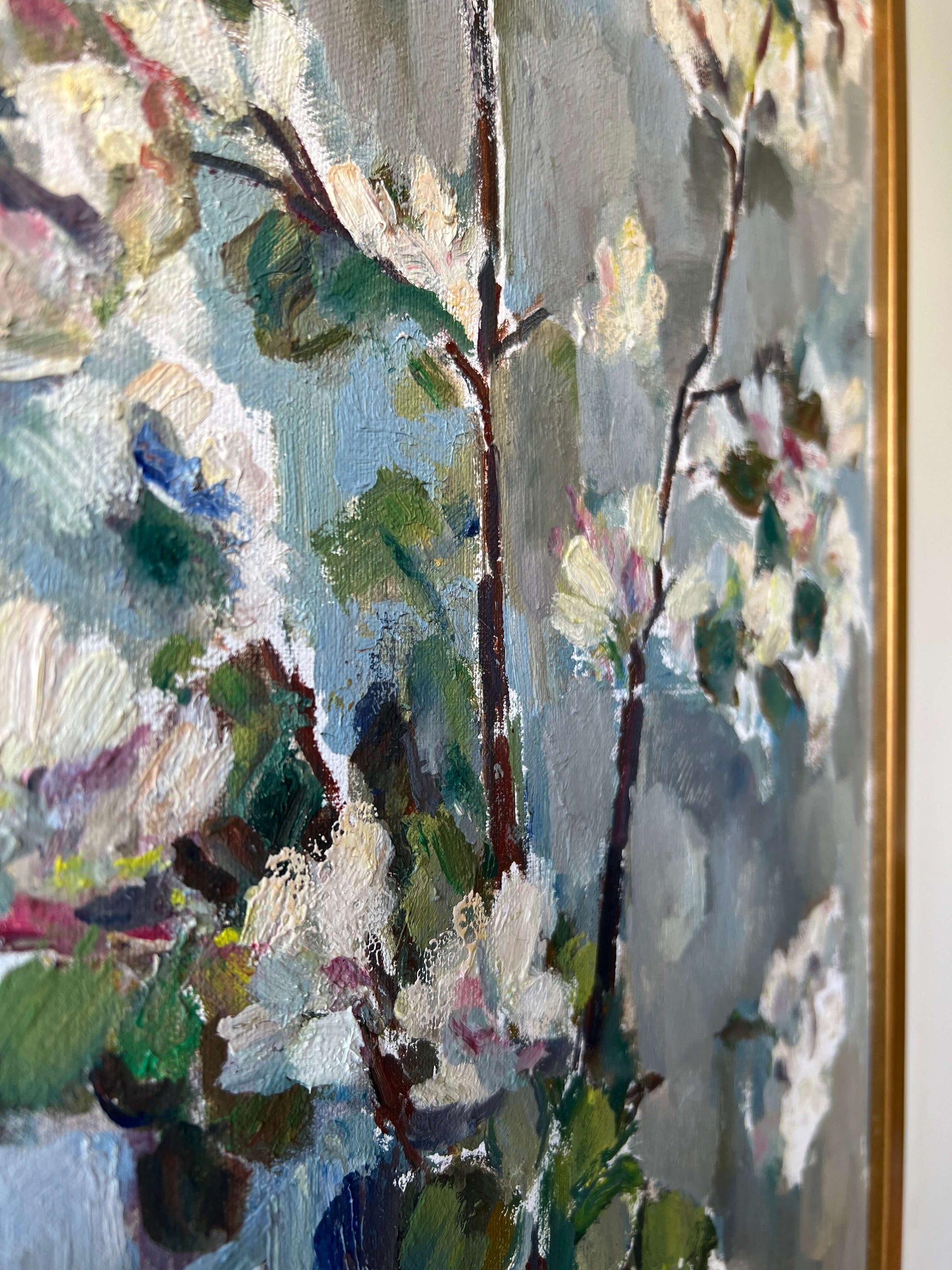 Close up of a framed vintage oil painting of white apple blossom flowers.
