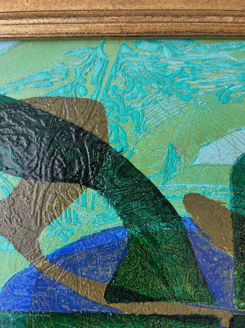 Close up of a framed, green & blue mixed media artwork with abstract design.