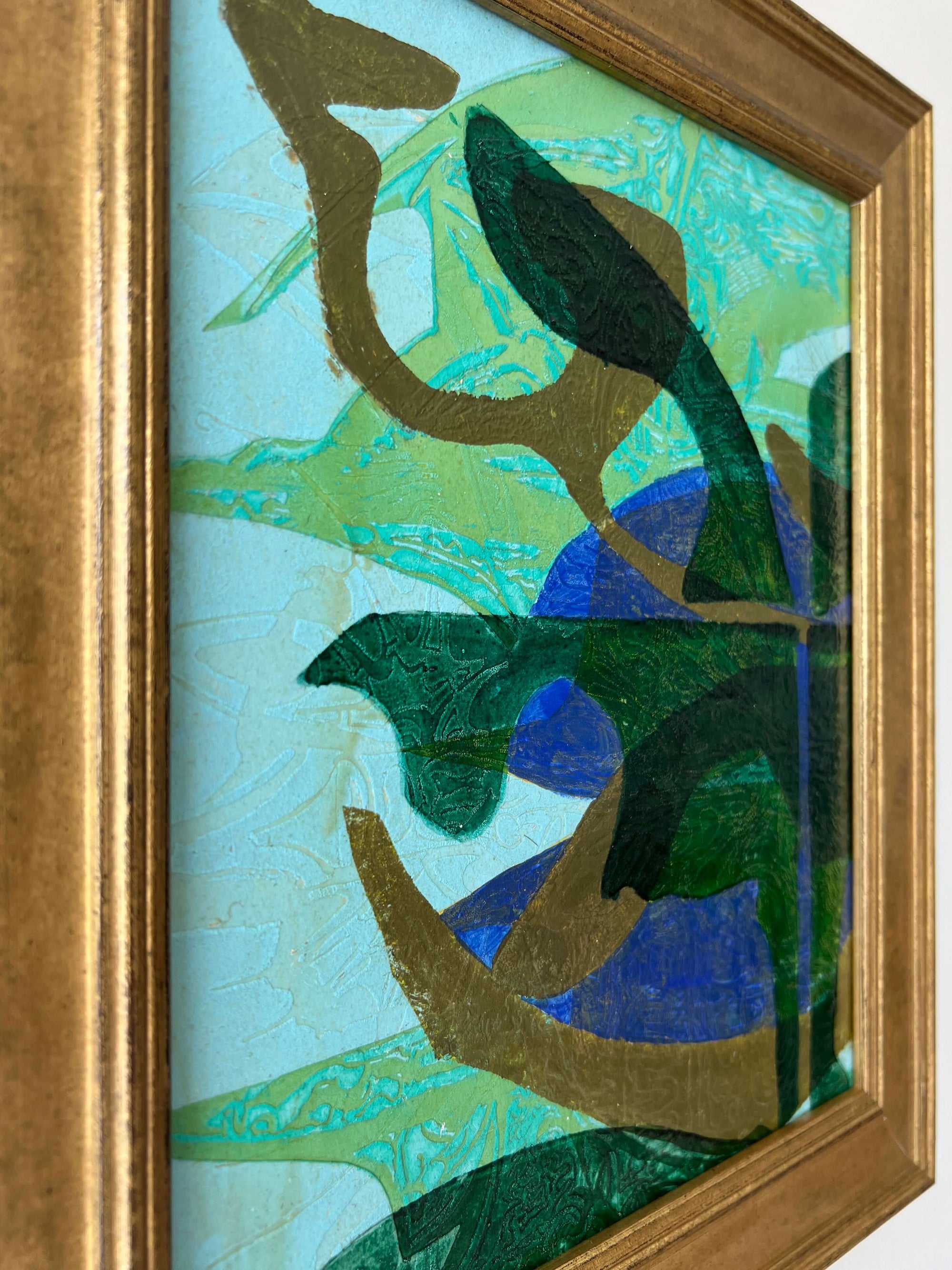 Close up of a framed, green & blue mixed media artwork with abstract design.