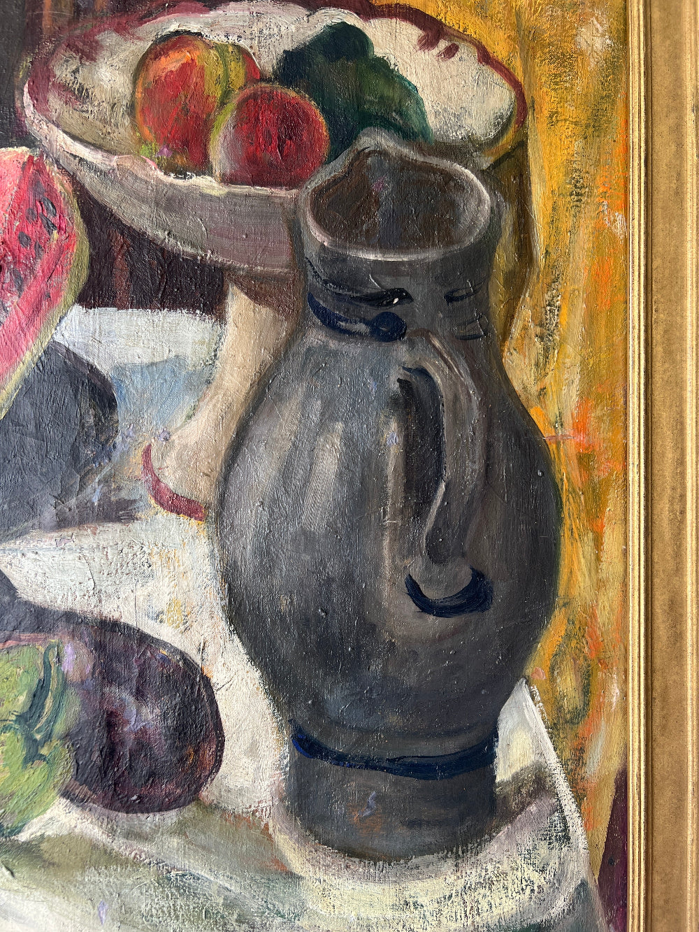 Close up of a framed still life oil vintage painting with watermelon, fruit, and jug on a table.