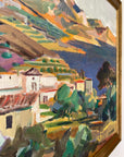 Close up of a framed, vintage oil painting on canvas of a mountainous coastal landscape with houses. Impressionist style.