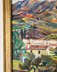 Close up of a framed, vintage oil painting on canvas of a mountainous coastal landscape with houses. Impressionist style.