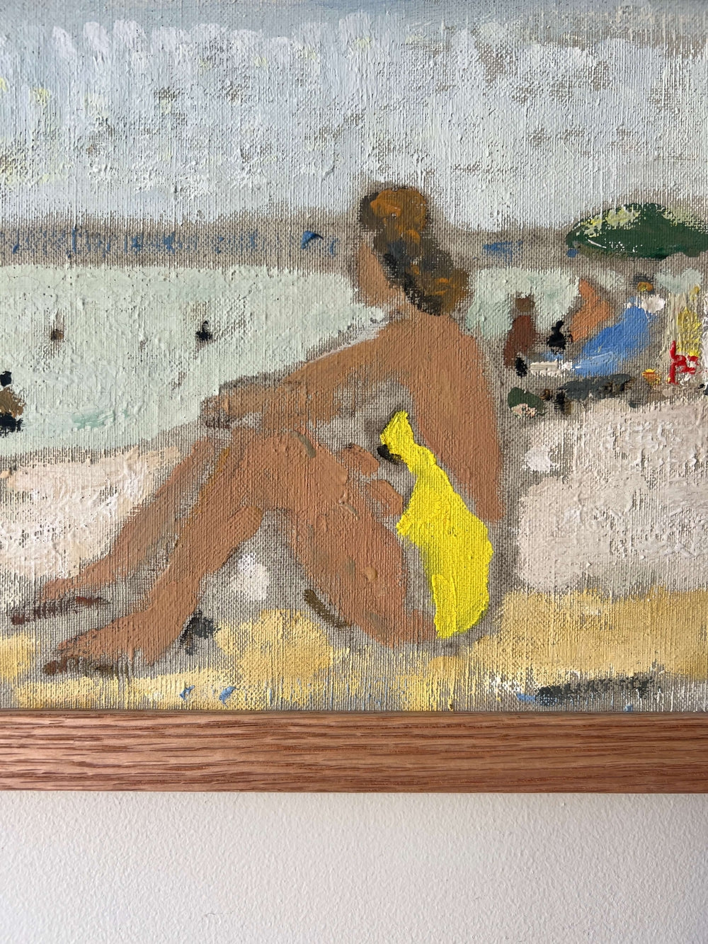 Close up of a framed artwork of a beach scene with figures