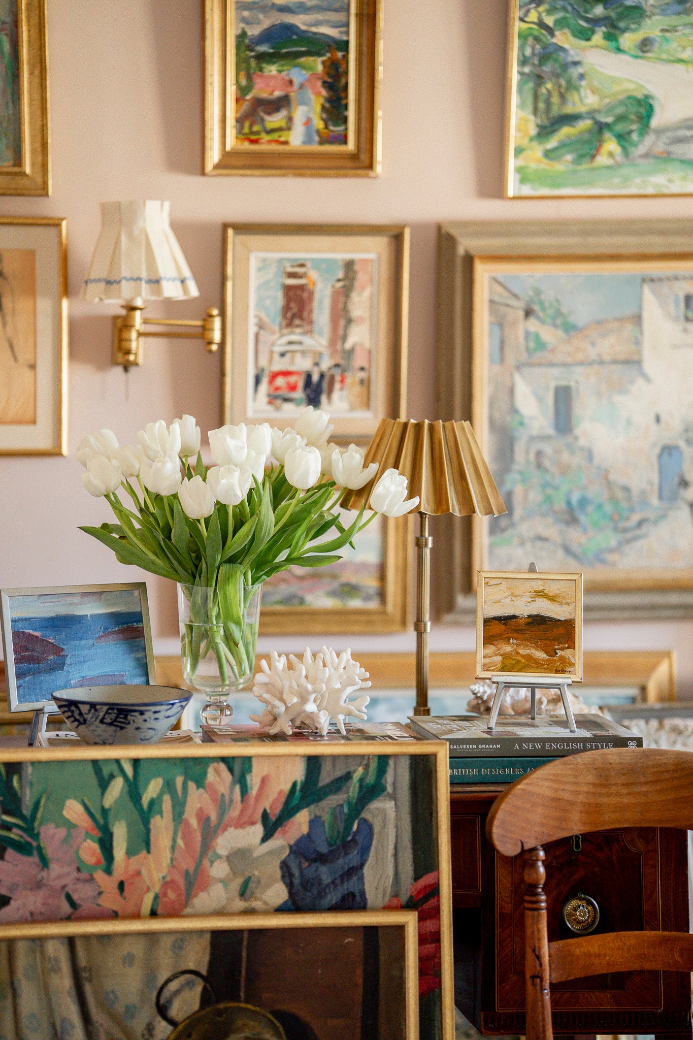 Decorative interior with a table, chair, lamp, and framed artworks on the wall.