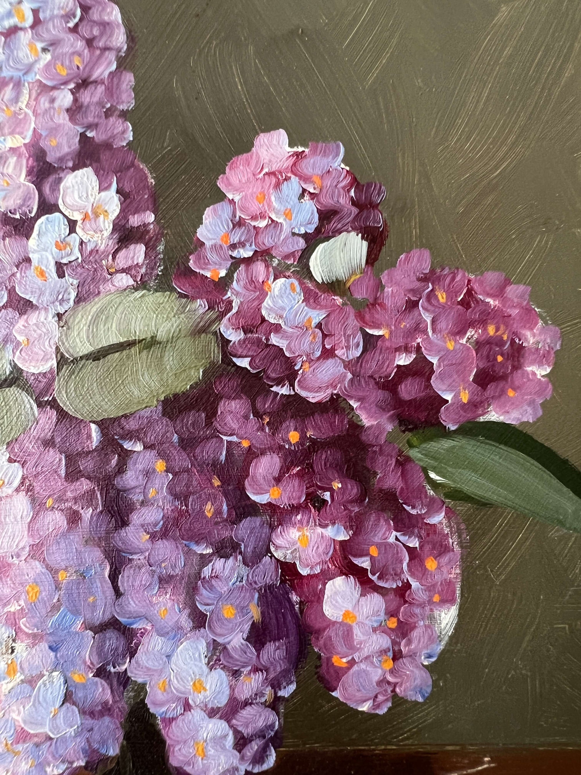Close up of a framed, vintage artwork of purple and white flowers on a dark background.