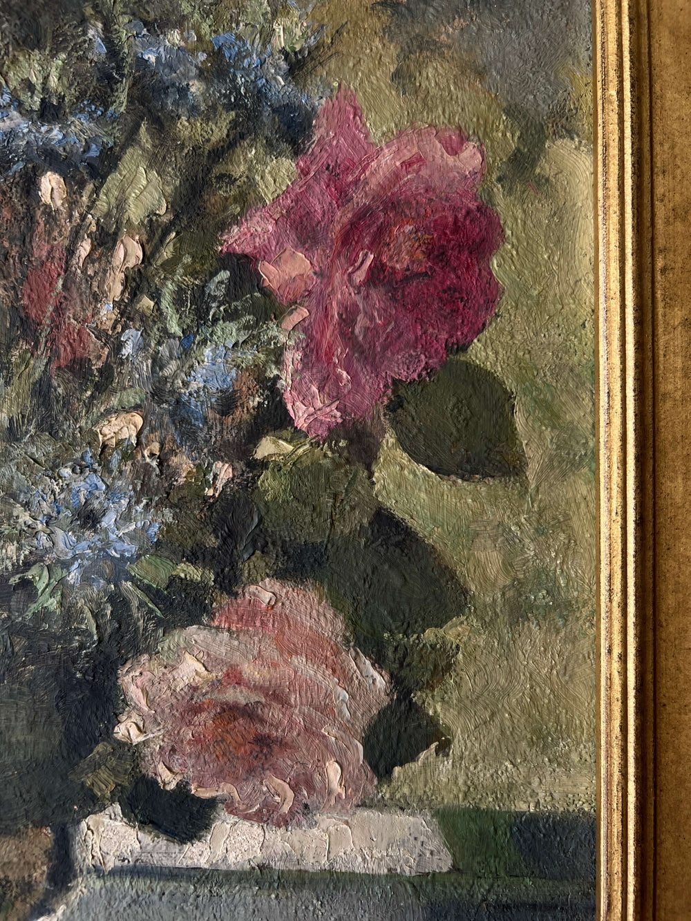 Close up of a vintage, framed oil painting of pink and blue floral. Signed by artist.