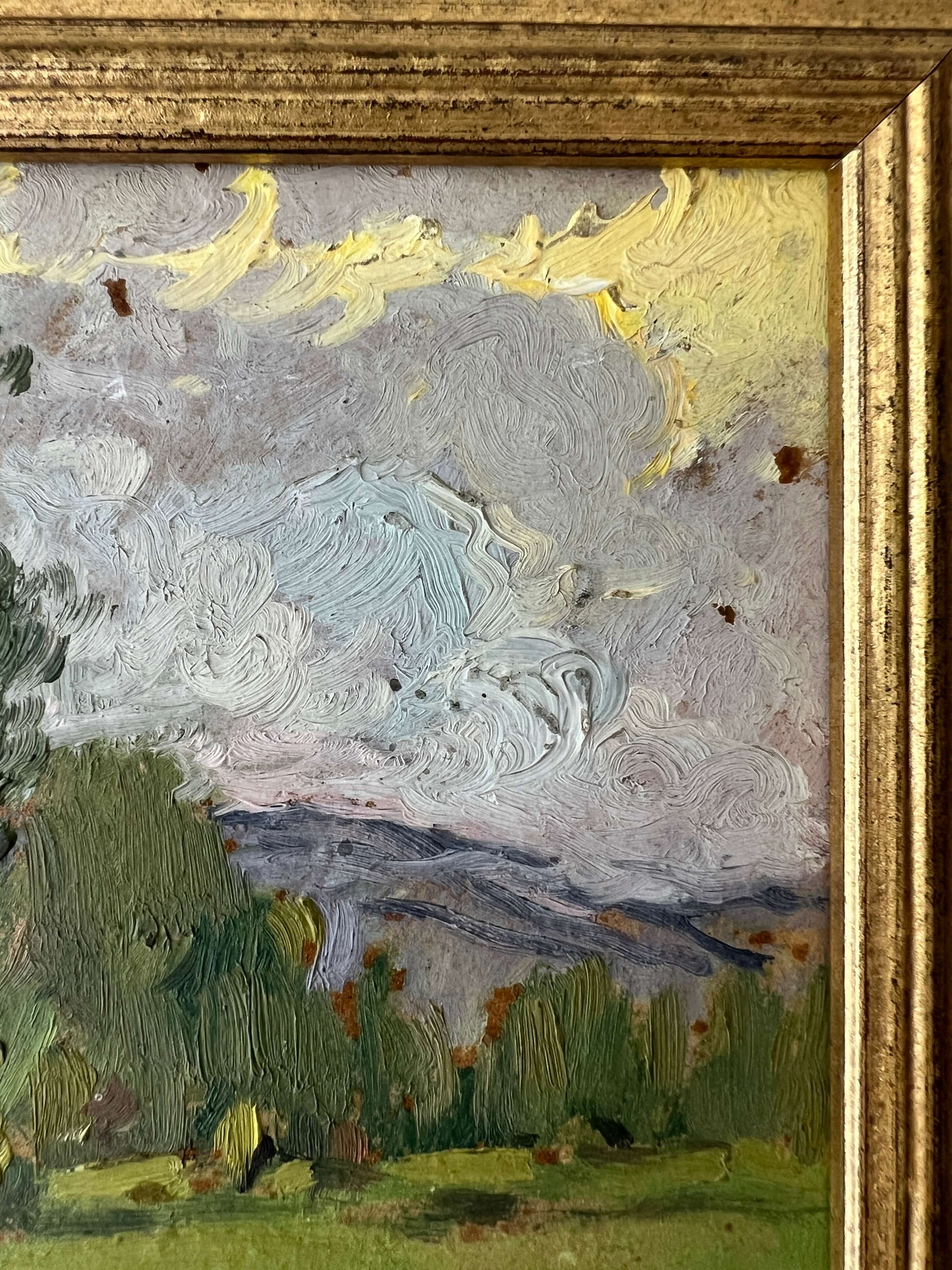 Close up of a framed vintage oil painting of a landscape with trees and a meadow.