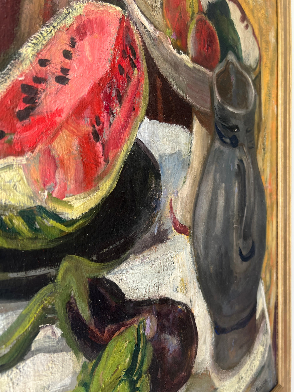 Close up of a framed still life oil vintage painting with watermelon, fruit, and jug on a table.