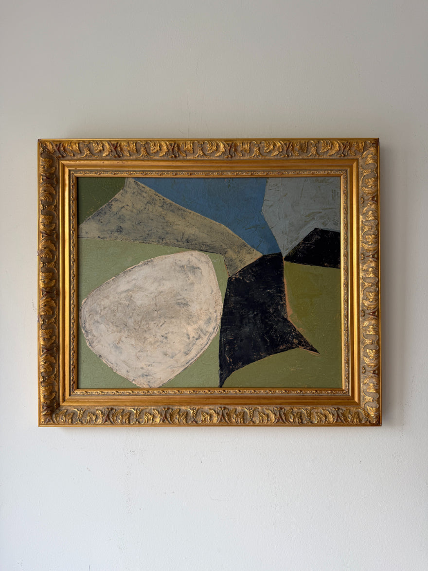 An abstract geometric oil painting in a wide ornate gold frame. The artwork features large organic shapes in cream, black, olive green, blue, and grey. Available at Hue. 