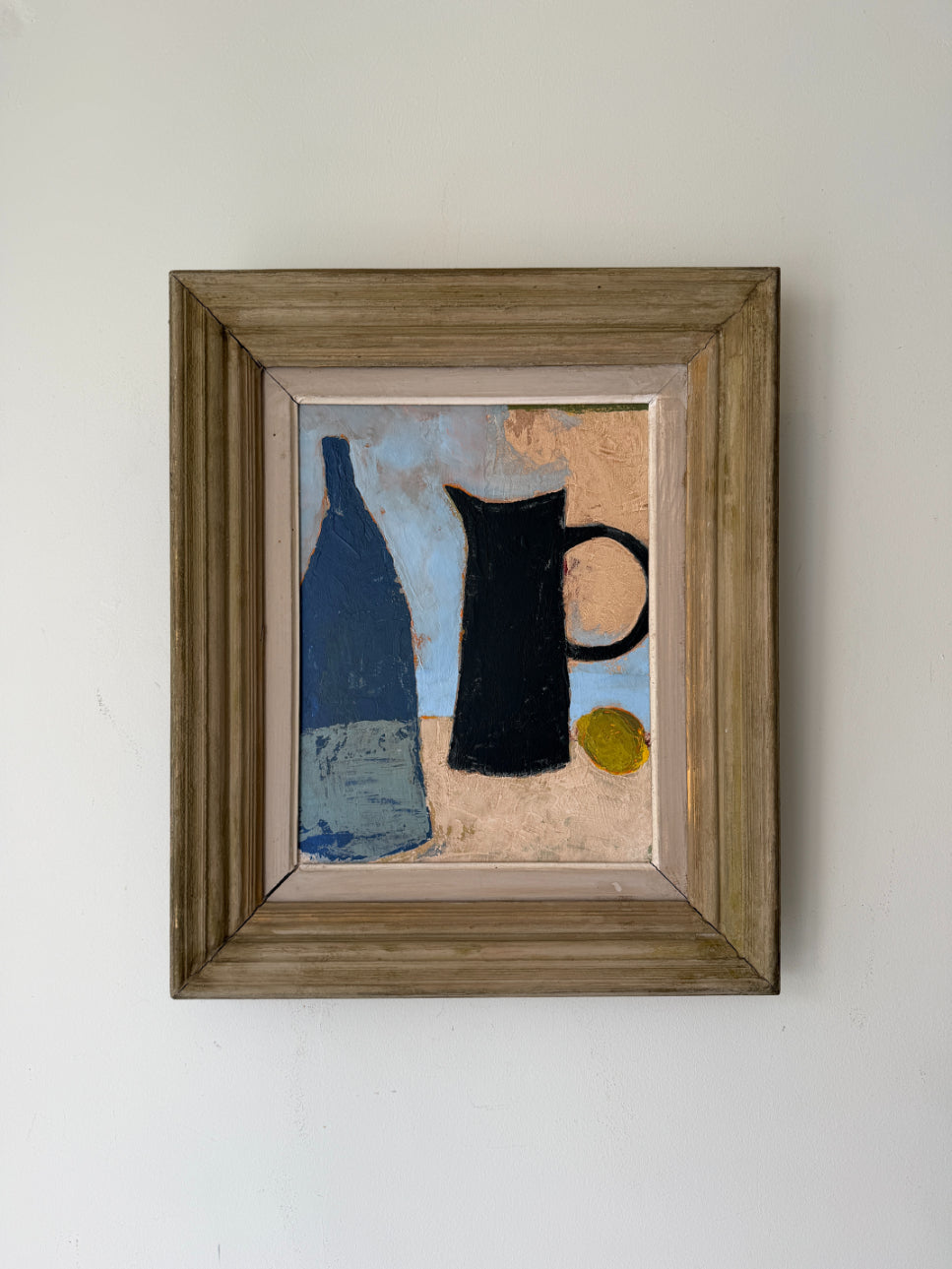 A framed still life painting featuring a blue bottle, a black pitcher, and a small yellow circle on a textured beige and blue background, housed in a rustic brown wooden frame. Available at Hue. 