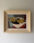 A framed abstract still life painting featuring yellow fruit in a white bowl. The artwork has bold geometric shapes in yellow, red, black, blue-gray, and beige, enclosed in a textured, vintage frame. Available at Hue. 