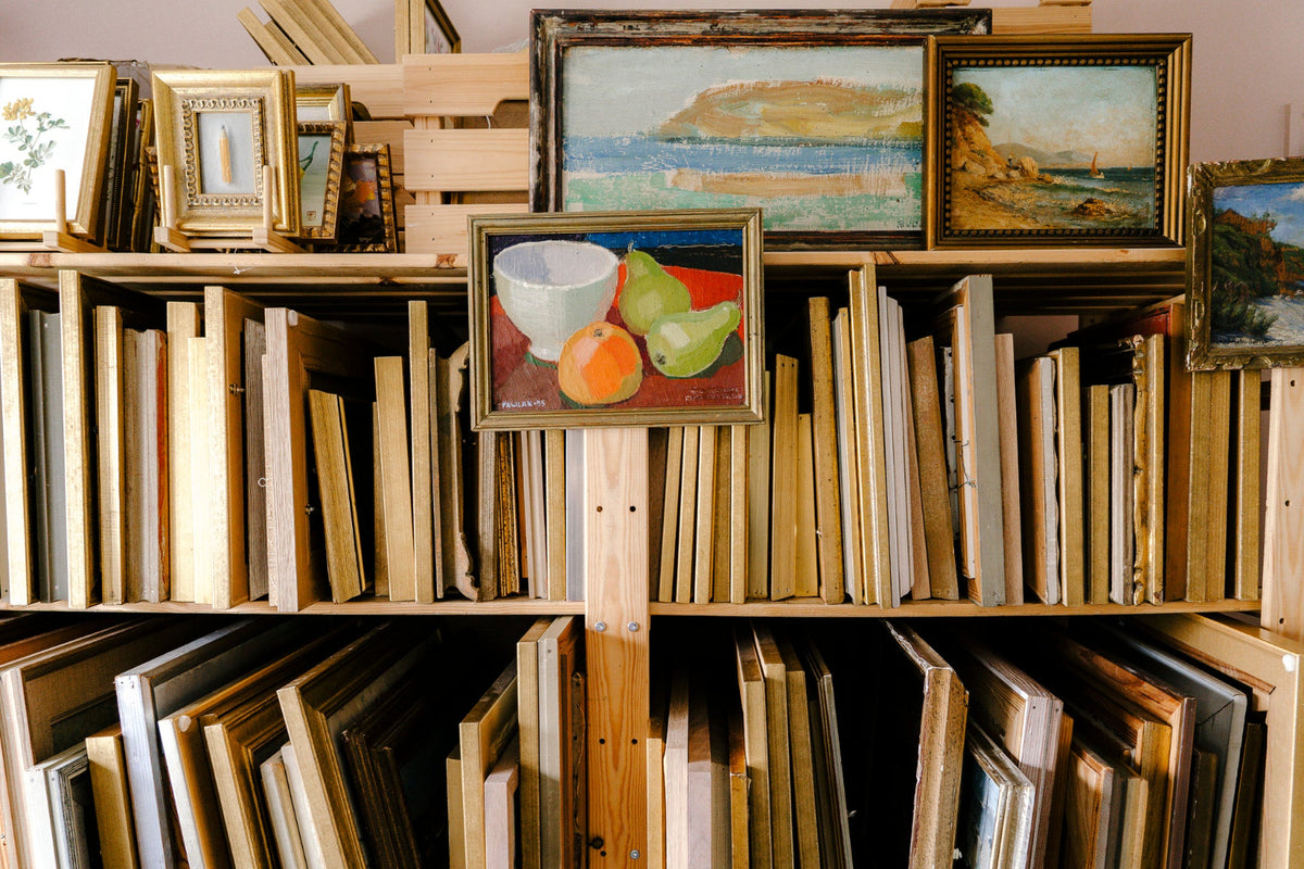 Collection of original French and Scandinavian mid-century vintage art and vintage oil paintings displayed on studio shelves.