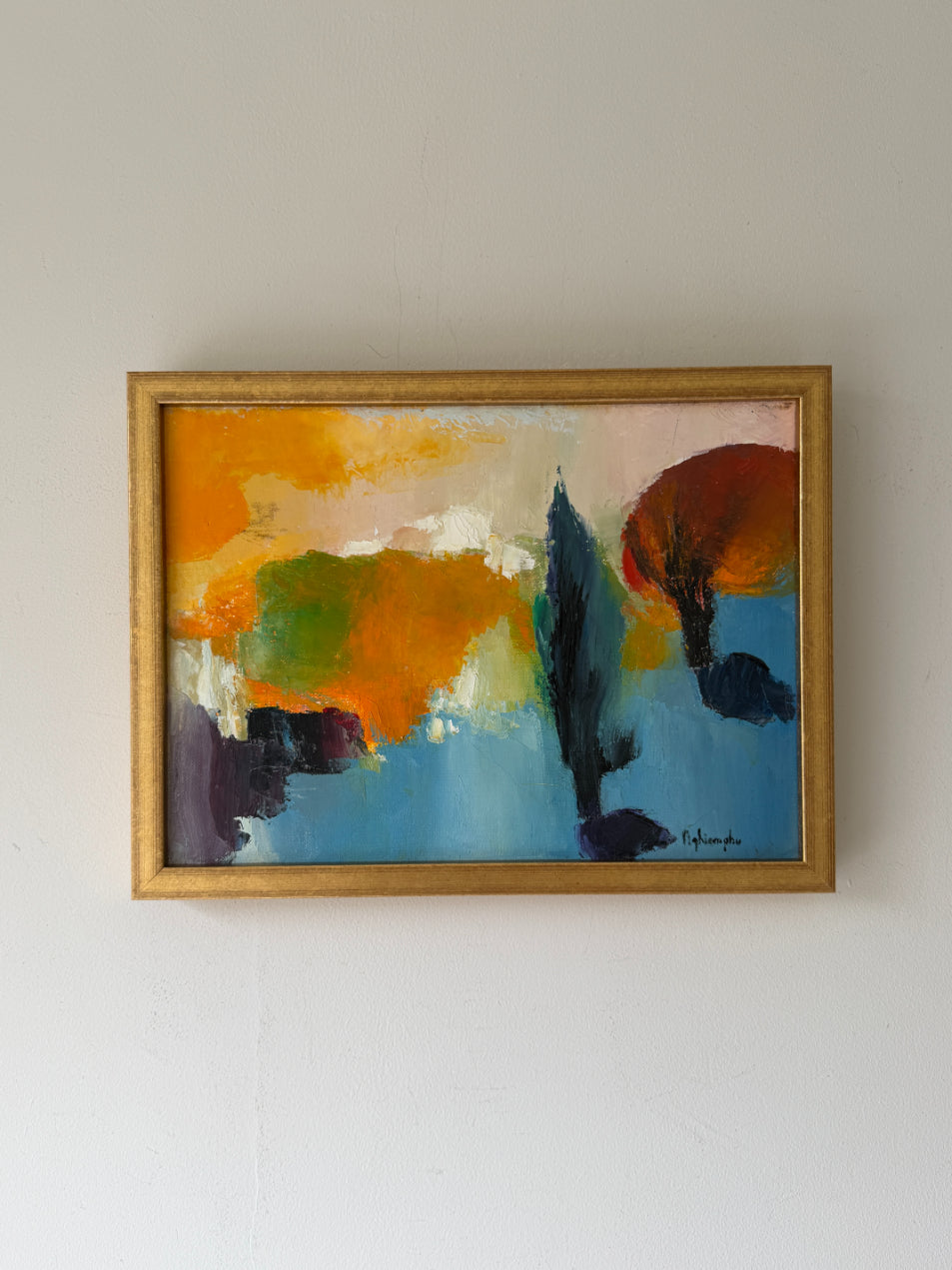 A vintage abstract landscape oil painting in a gold frame.The painting features expressive brushstrokes of orange, yellow, green, blue, and dark brown. Available at Hue. 