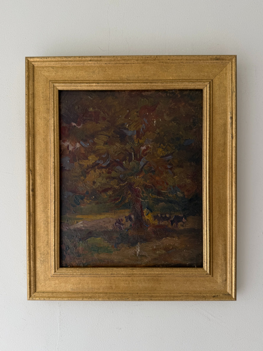 A framed vintage oil painting depicting a dark, moody forest scene with trees and cows. Available at Hue. 