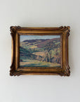 Framed vintage oil painting of a rolling green landscape in France. Presented in an ornate gilt frame. Available at Hue. 