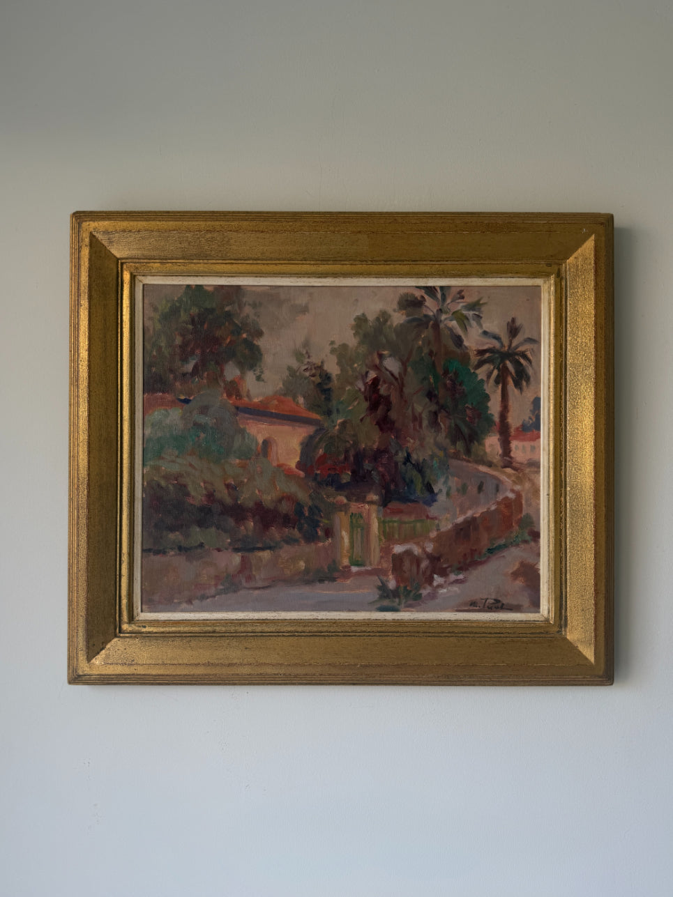 A framed vintage landscape painting depicting a tropical scene with palm trees, a stone wall, country villa, and a pathway, housed in a textured gold frame.  Available at Hue. 