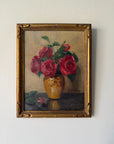 A framed vintage oil painting of red roses in a yellow vase. Available at Hue. 