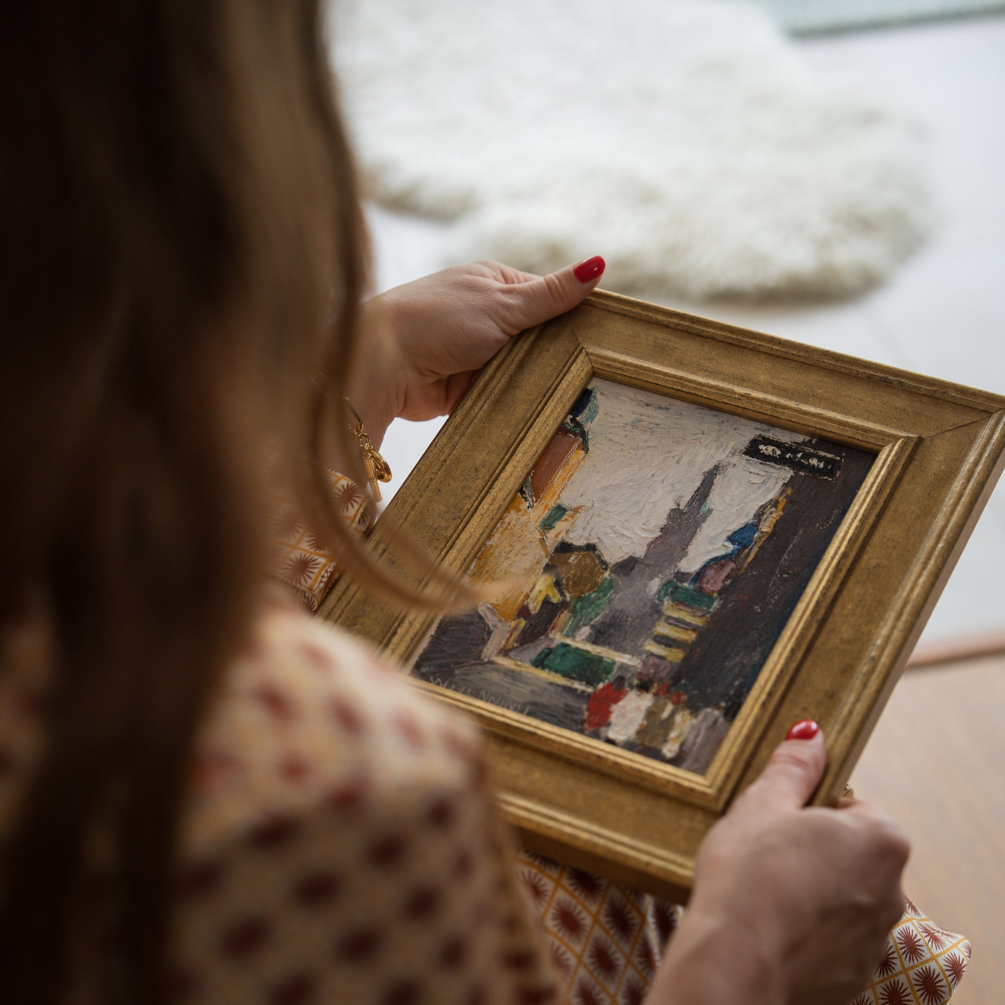 hands holding a framed colourful cityscape vintage painting in a gold frame available from hue