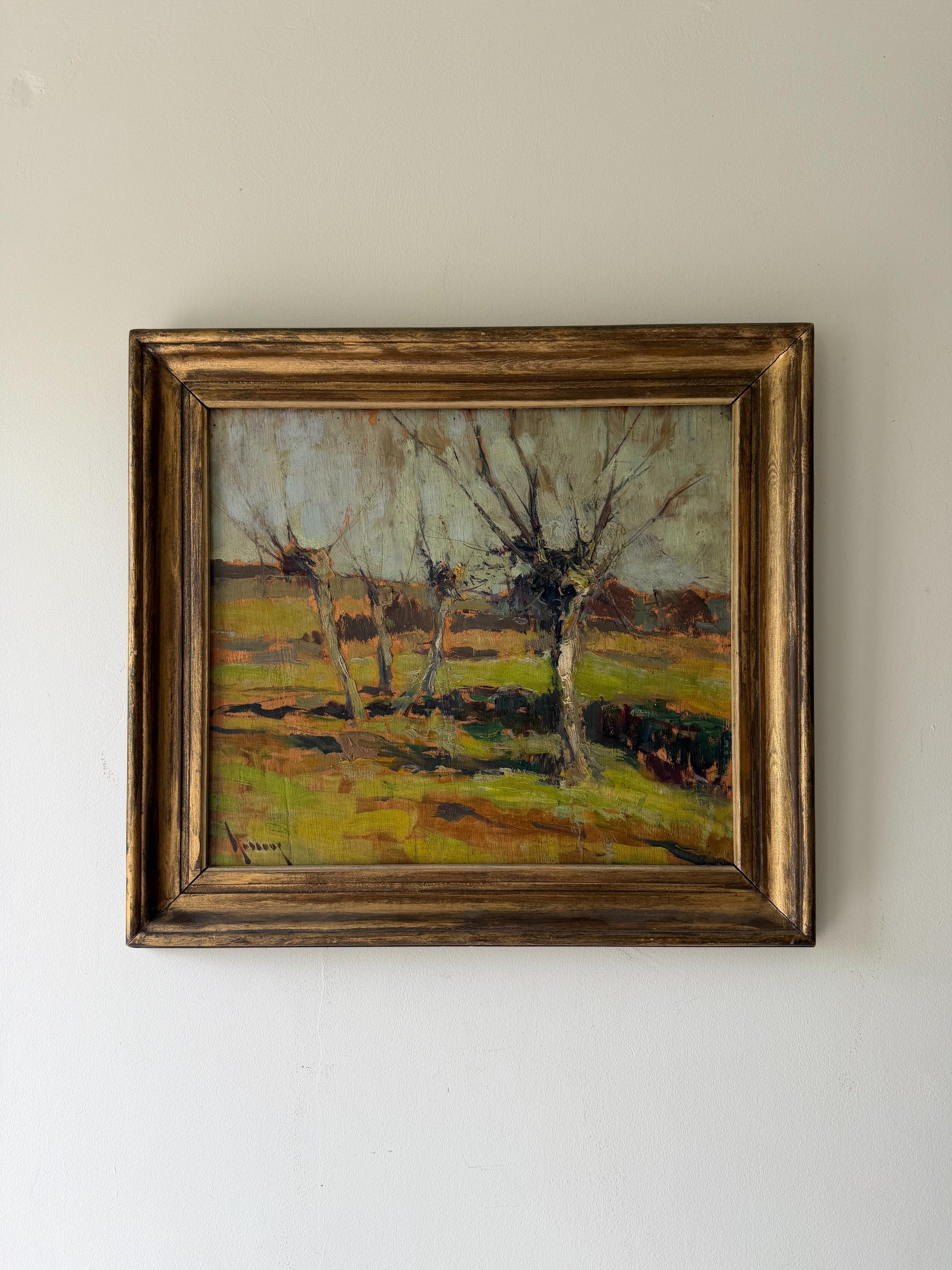 A framed vintage oil landscape painting featuring leafless trees in a grassy field. Available at Hue. 