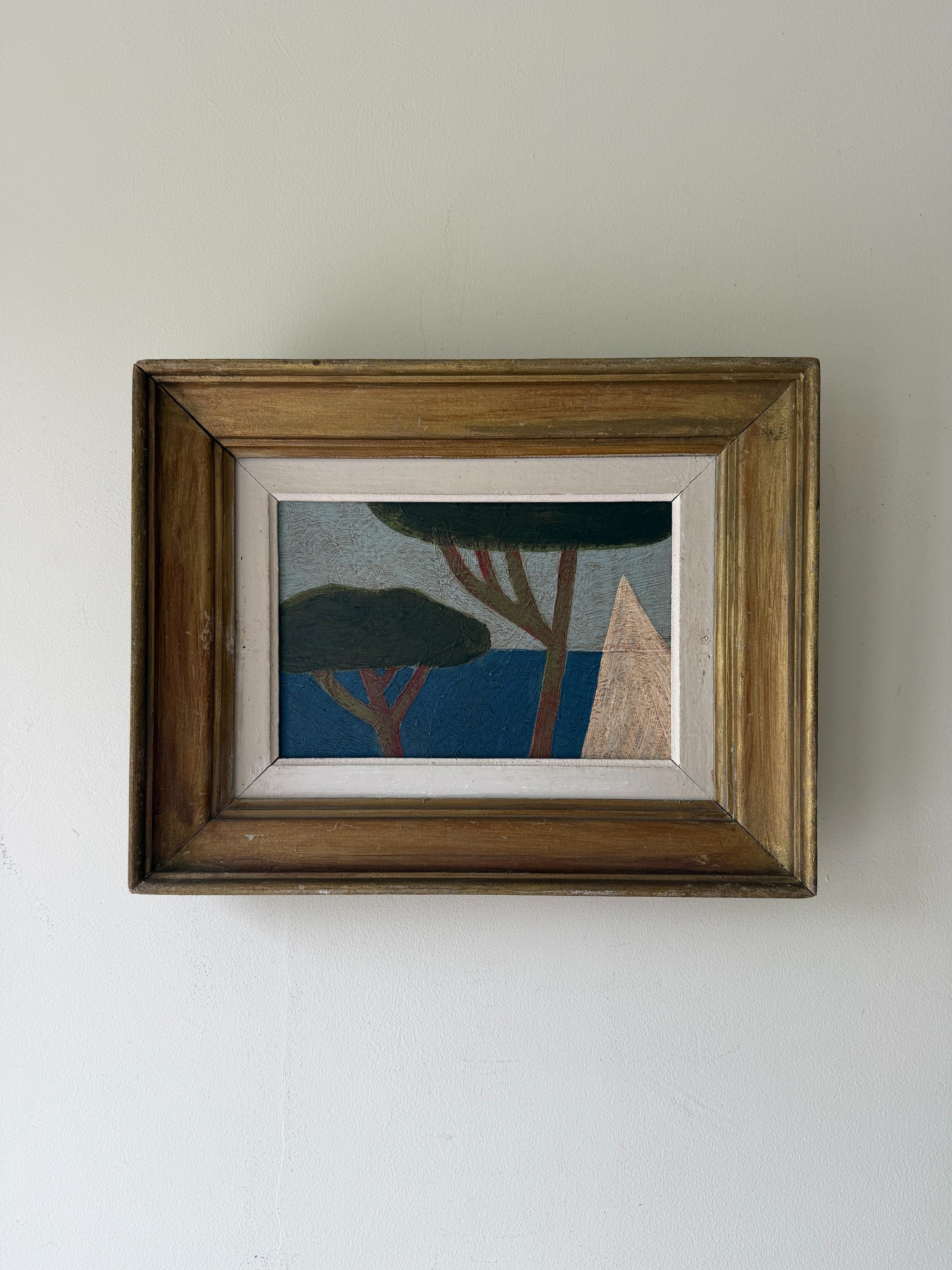 A framed oil painting featuring a minimalist landscape with blue water and dark green trees. Available at Hue. 