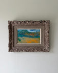 A small framed landscape painting with an ornate, distressed vintage frame. Available at Hue. 