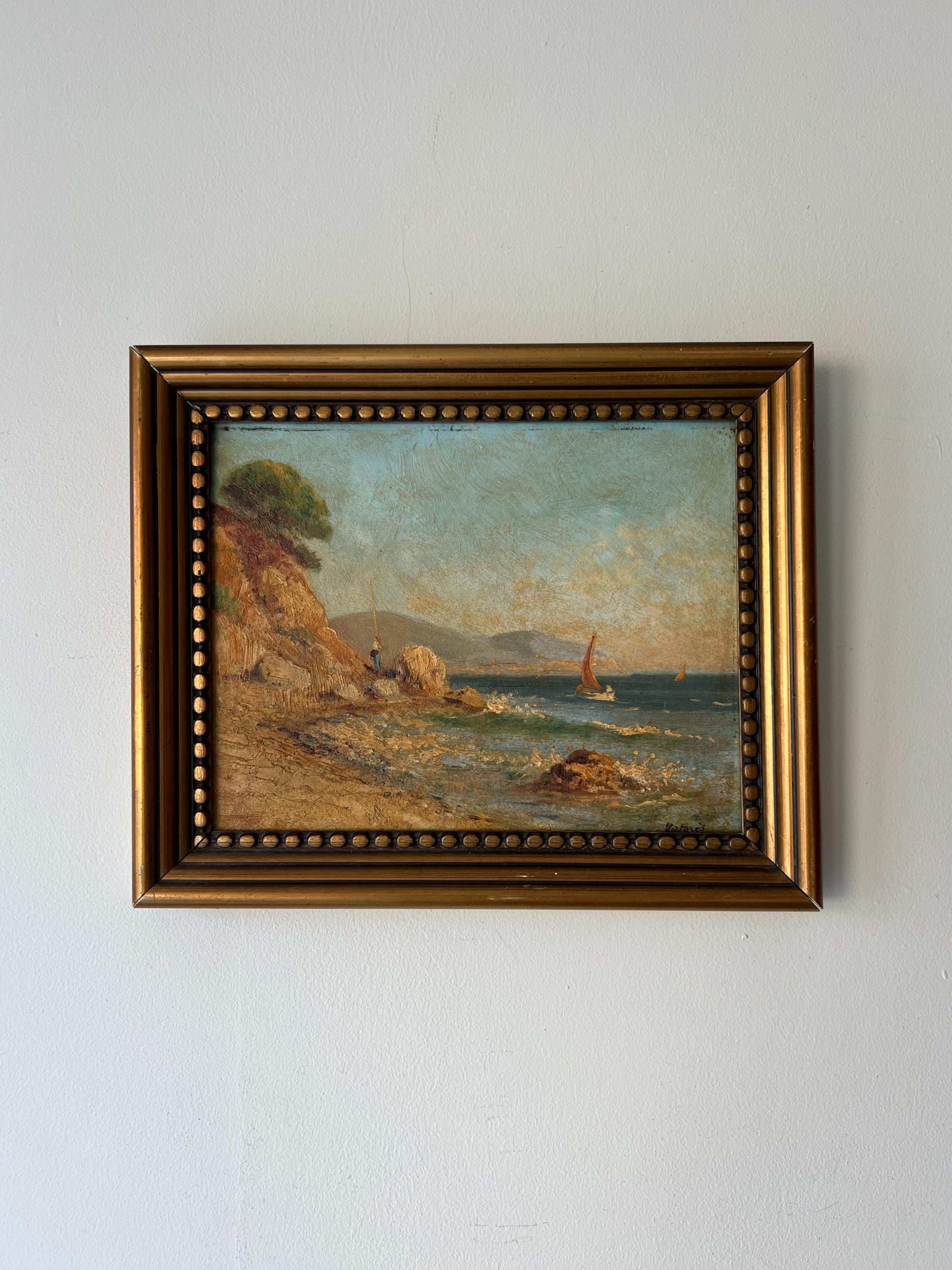 Framed vintage oil painting of a coastal scene with a sailboat. Available at Hue.