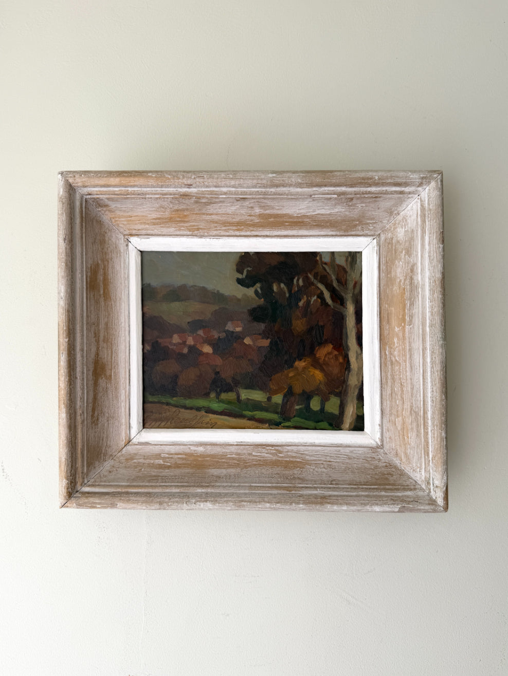 Framed vintage oil painting of a landscape with trees and a distant village. Available at Hue. 