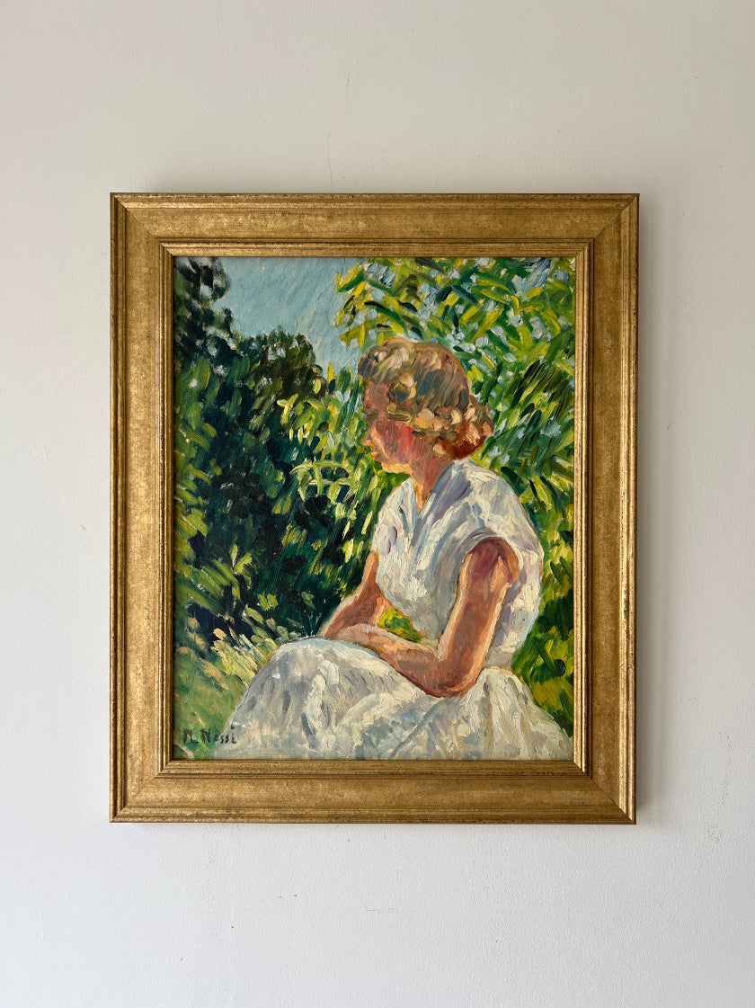 A framed vintage oil painting of a girl seated in dappled light in a garden. Available at Hue. 